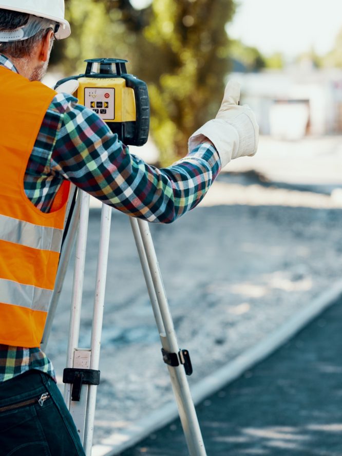 Engineer in reflective vest using equipment during geodetic work